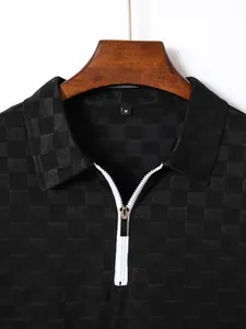 Close-up detail of men's black checkered jacquard polo shirt with white zipper collar