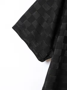 Close-up of black plaid jacquard fabric texture on a men's polo shirt sleeve
