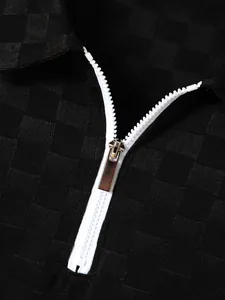 Close-up of white zipper on black checkerboard jacquard polo shirt fabric
