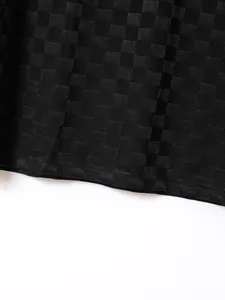 Detailed macro view of the black checkered jacquard fabric on a men's sport polo shirt.