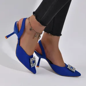 Close-up of elegant blue satin pointed-toe stiletto heels featuring a sparkling rhinestone buckle