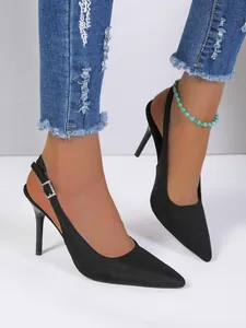 Elegantes salones de aguja negros de punta con tira trasera y hebilla de strass.