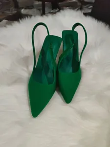 Μυτερές γόβες slingback σε έντονο πράσινο πάνω σε λευκό φόντο από ψεύτικη γούνα