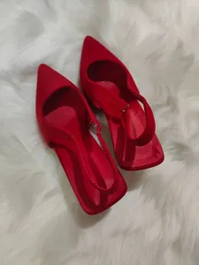 Κομψές κόκκινες μυτερές γόβες slingback σε φόντο από λευκή συνθετική γούνα.