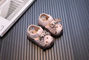 Nahaufnahme von rosa Baby-Sandalen für Mädchen mit karierter Schleife und Stickerei