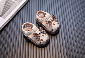 Detailansicht von Baby-Mädchen-Sandalen mit dekorativer Schleife und Blumenstickerei