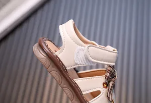 Nahaufnahme einer Baby-Sandalette für Mädchen mit Klettverschluss und karierter Schleife
