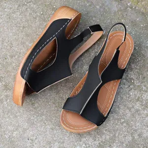 Détail de sandales noires ajourées pour femmes avec coutures blanches et semelles fauves