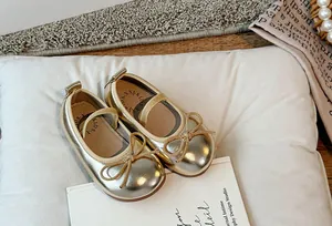 Dettaglio di scarpe Mary Jane dorate per bambine con fiocco carino e suola morbida