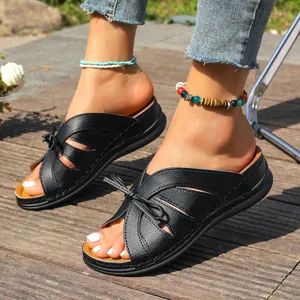 Nahaufnahme von eleganten schwarzen Plateau-Keilsandalen mit Schleifendetail auf Holzdeck