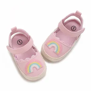 Vista dall'alto di scarpe primi passi rosa per neonati con dettaglio arcobaleno ricamato