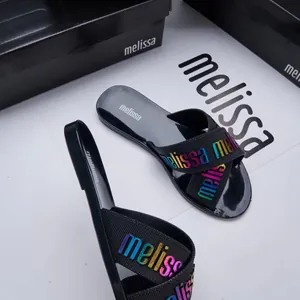 Detail of black jelly cross-strap slide sandals featuring colorful gradient letter design