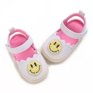 Dettaglio di scarpe primi passi morbide per neonati con simpatica toppa smiley gialla.