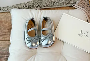 Dettaglio delle scarpe argentate da bambina con suola morbida e un grazioso fiocco decorativo