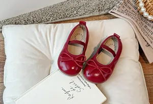 Dettaglio di scarpe Mary Jane rosse per bambine con fiocco carino e cinturino elastico