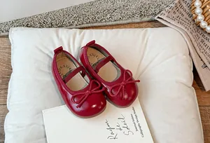 Primo piano di eleganti scarpe Mary Jane rosse per bambini con fiocco