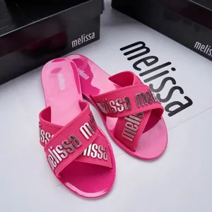 Close-up of fuchsia Melissa jelly cross-strap slides with metallic brand letters.