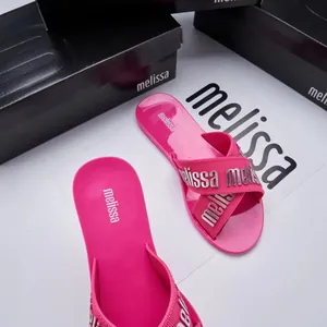 Close-up of pink Melissa jelly slides with silver letter detail on cross-straps