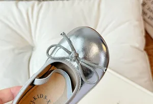 Primo piano dettagliato delle ballerine in argento metallizzato per bambina con fiocco