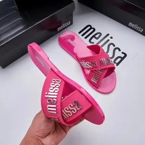 Detail view of pink Melissa jelly slides with crisscross straps and metallic logo
