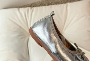Primo piano di ballerine argentate da bambina che mostra la texture della pelle metallizzata.