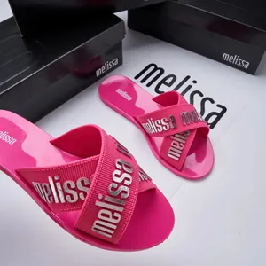 Detailed view of pink Melissa jelly cross-strap slides with silver lettered straps