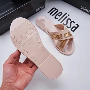 Close-up detail of Melissa jelly cross strap slides with gold logo lettering and textured sole