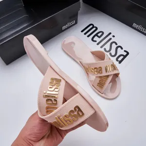 Detailed view of pink Melissa jelly slides featuring cross straps and gold lettering