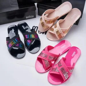 Melissa jelly slide sandals with metallic cross straps and signature logo branding in black and pink