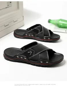 Detailweergave van zwarte leren heren slippers met stijlvolle witte contraststiksels