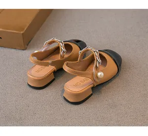 Detail view of girls' khaki and black color-block sandals with pearl and chain accents.