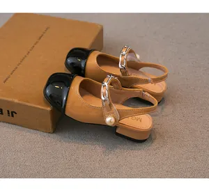 Detailed view of girls' patent leather sandals with pearl and chain accents.