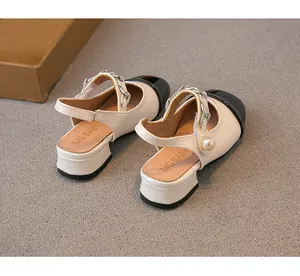 Detailed view of girls' cream and black sandals featuring pearl and chain strap accents.