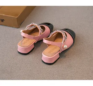 Detailed macro view of pink and black girl's sandals with pearl and chain accents