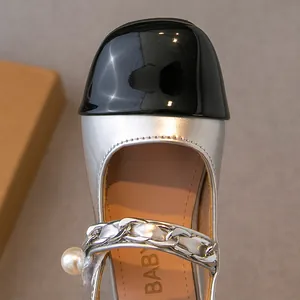 Close-up of girls' silver Mary Jane sandals with black toe cap and pearl chain strap