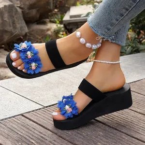 Wedge platform sandals with blue floral embellishments shown in an outdoor setting.