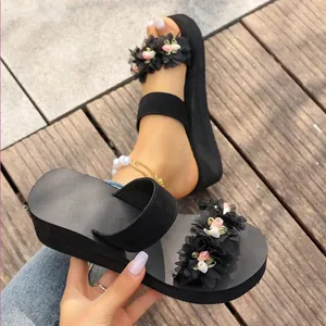 Macro view showing intricate floral decorations on black wedge platform beach sandals