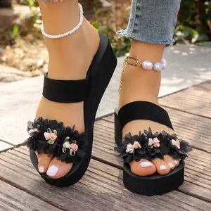 Close-up of black platform wedge sandals with decorative flowers and pearl anklets