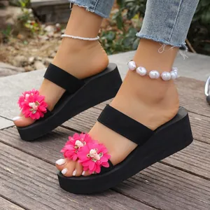 Close-up of bright pink flower decorations on stylish black platform wedge sandals