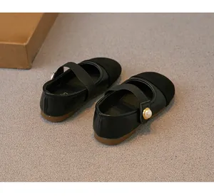 Detailed view of girls' black Mary Jane shoes with pearl strap decoration and suede toe.