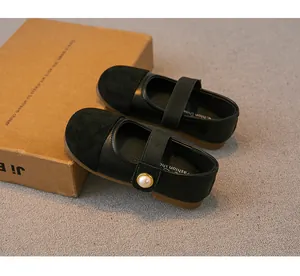 Close-up of girls' black Mary Jane shoes with pearl buckle and suede toe detail