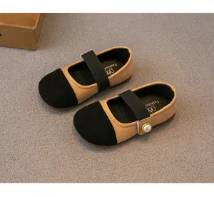 Close-up detail of toddler girl's black and tan Mary Jane shoes with a pearl accent buckle