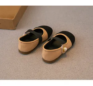 Close-up of comfortable beige and black girls' Mary Jane shoes with elegant pearl button detail.