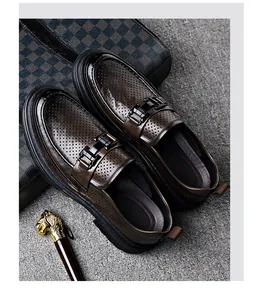 Detailed view of brown men's hollow-out leather loafers with stylish metal buckle accents