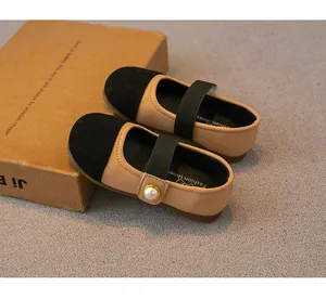Detailed view of girls' beige Mary Jane shoes with black toe cap and pearl detail.
