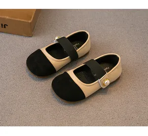 Close-up of girls' beige and black Mary Jane flats with pearl button details.