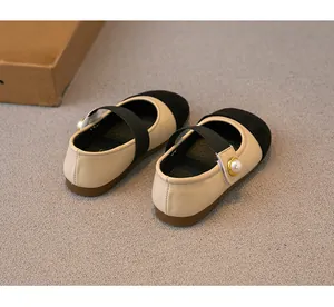 Detailed view of kids beige and black Mary Jane flats with elegant pearl button strap