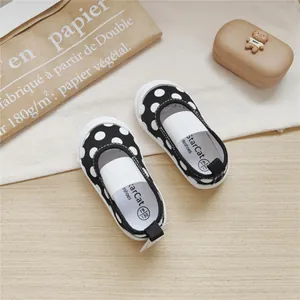 Close-up of black and white polka dot toddler canvas shoes with soft square mouth design