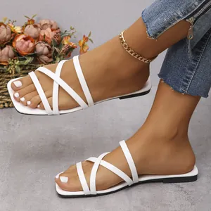 Detalle de sandalias planas blancas con punta cuadrada y diseño de tiras cruzadas