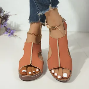 Close-up van oranje uitgesneden sleehaksandalen met decoratieve witte stiksels.